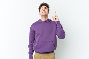 Young caucasian man isolated on white background indicates with both fore fingers up showing a...