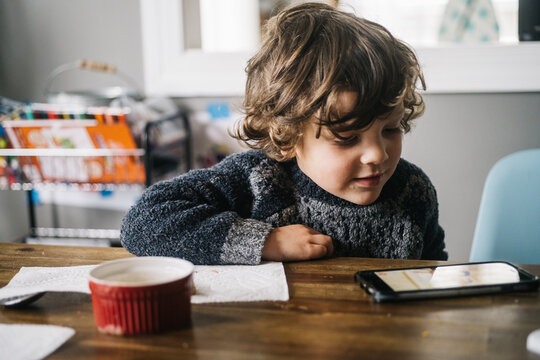 Young boy watching shows on his phone during lunch