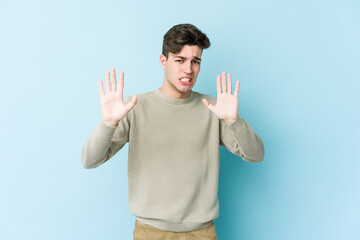 Young caucasian man isolated on blue background rejecting someone showing a gesture of disgust.