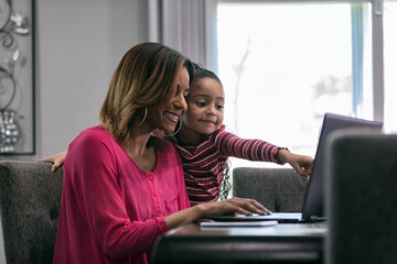 Home: Little Girl Points At Screen While Mother Works From Home