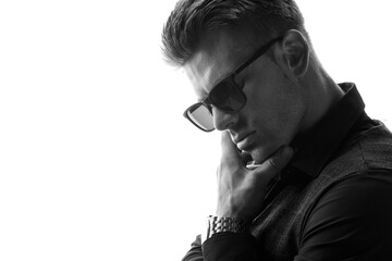Black and white portrait of beautyful guy on white background. High fashion model posing in studio. Attractive man in classic suit and sunglasses.