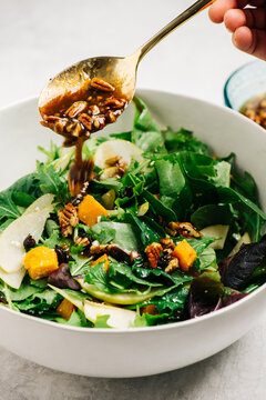 Drizzling vinaigrette over a salad