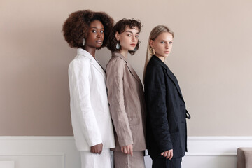A small group of fashion multiracial multiethnic young beautiful sensual models are posing near the wall in studio room