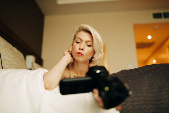 young blond woman with small camcorder on the bed