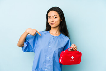 Young chinese nurse woman isolated on a blue background dreaming of achieving goals and purposes
