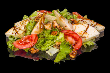 Delicious mixed salad with pear,  lettuce, tomatoes, nuts and sauce with reflection,