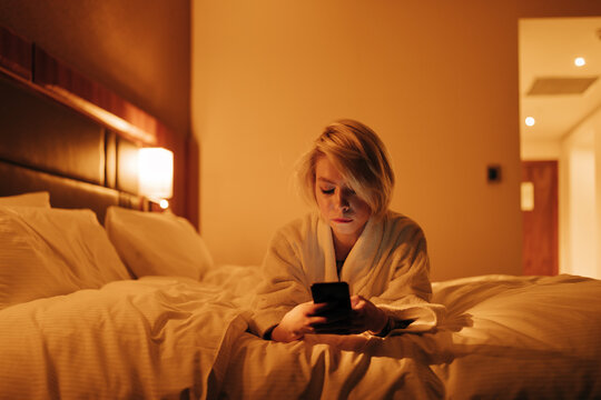 young woman with cell phone on the bed