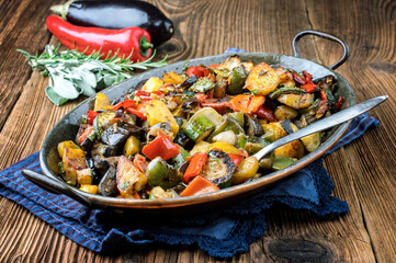 Traditional French vegetable ratatouile offered as close-up in a rustic casserole on a wooden table