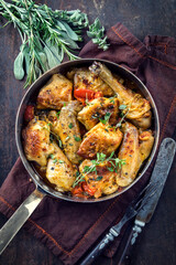 Traditional French lemon chicken in sauce offered with tomatoes as top view in a rustic casserole