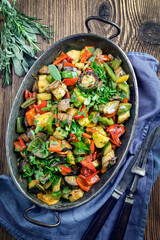 Traditional French vegetable ratatouile offered as top view in a rustic casserole on a wooden table