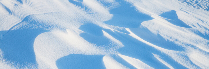 Snow texture. Wind sculpted patterns on snow surface. Wind in the tundra and in the mountains on the surface of the snow sculpts patterns and ridges. Arctic, Polar region. Winter panoramic background.