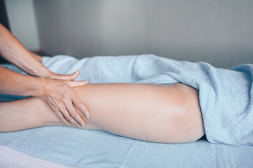 Young unrecognizable woman lying on massage table and enjoying therapeutic massage. Body care, losing weight concept. Hands masseur massage therapist doing anti-cellulite massage in spa clinic.