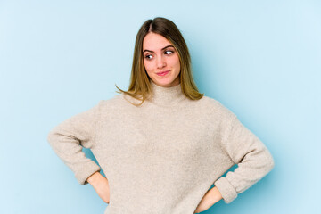 Young caucasian woman isolated on blue background dreaming of achieving goals and purposes