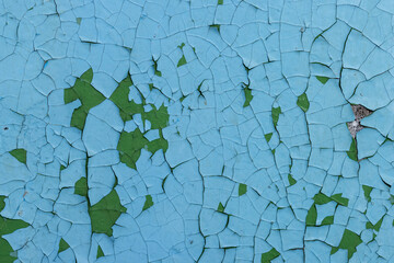 Peeling paint on the wall. Old concrete wall with cracked flaking paint. Weathered rough painted surface with patterns of cracks and peeling. Grunge texture for background and design. High resolution.