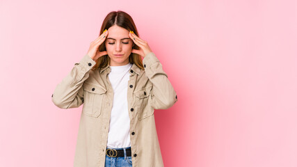 Young caucasian woman isolated on pink background touching temples and having headache.