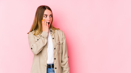 Young caucasian woman isolated on pink background being shocked because of something she has seen.