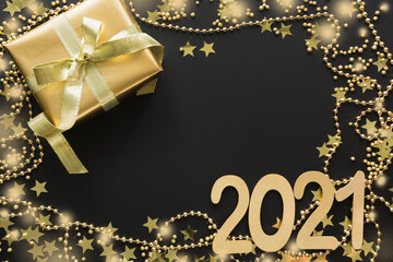 Fototapeta na wymiar Christmas creative shiny border of golden beads, gift on black background with date 2021 New Year.