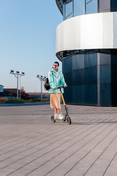 Pretty young brunette beautiful woman are riding electric scooter in summer in town