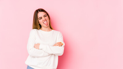 Obraz premium Young caucasian woman isolated on pink background funny and friendly sticking out tongue.
