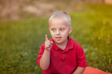 Portrait of a little cute boy with Down Syndrome, caring for sick people, genetic disease,...