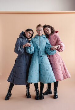 Fashion style studio portraits of beautiful woman posing in winter vogue stylish design coats on creamy pastel background.