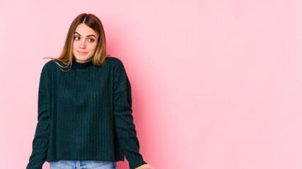 Young caucasian woman isolated on pink background shrugs shoulders and open eyes confused.