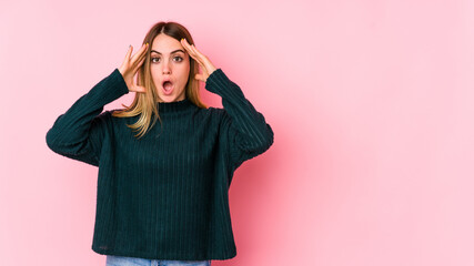 Young caucasian woman isolated on pink background receiving a pleasant surprise, excited and...