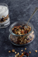 Granola in a glass jar with granola and yogurt cup in the background