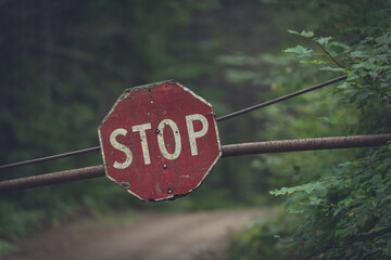 Close up of a stop sign on a gate in Algonquin Park Canada. Blurred trees and road in the...