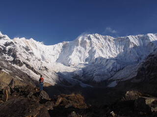 A mountain climber standing in front of a snow-covered Himalayas in the blue skies, ABC (Annapurna...
