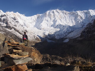 A mountain climber standing in front of a snow-covered Himalayas in the blue skies, ABC (Annapurna...