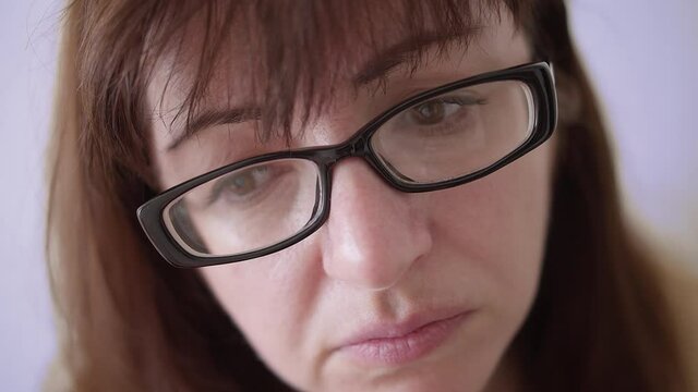 woman with glasses looks with an accusingly scrutinizing look, close up