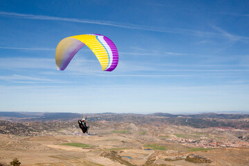 Paraglider feeling free flying in the mountains in a sunny day
