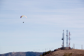 paraglider flying in front of a few antennas of mobile phone