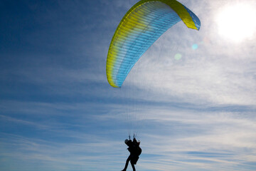 silhouette of a man with a paraglide in a sunny day with a sunny sky