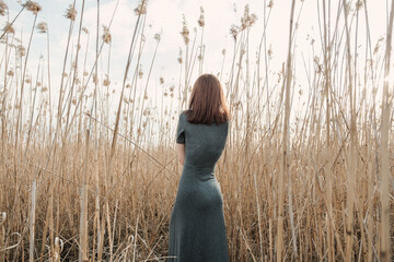 young girl stands with her back in the grass