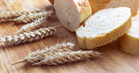 Fototapeta na wymiar Sliced bread on a wooden board, with wheat spikelets.