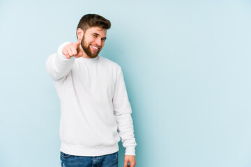 Young caucasian man isolated on blue background cheerful smiles pointing to front.
