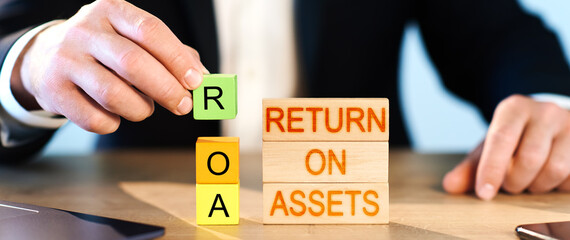 roa concept. a man puts wooden blocks in the inscription return on assets