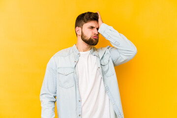 Fototapeta premium Young caucasian man isolated on yellow background forgetting something, slapping forehead with palm and closing eyes.