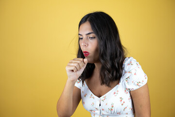 Beautiful woman over yellow background feeling unwell and coughing as symptom for cold or bronchitis. Healthcare concept.