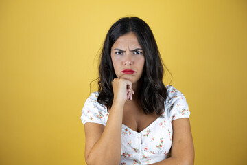 Beautiful woman over yellow background with angry expression with crossed arms