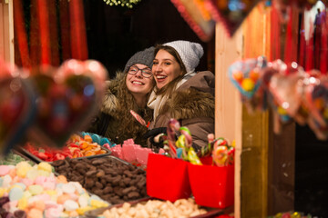 Two beautiful girls choosing candies at an outdoor candy stan