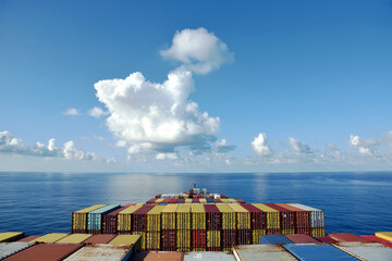 Fully loaded container ship sailing through a blue, calm ocean. View on the stack of the containers...