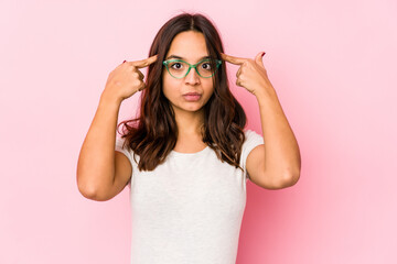 Young mixed race hispanic woman isolated focused on a task, keeping forefingers pointing head.
