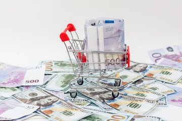 on a large amount of money spread out on the table stands a supermarket trolley filled with euro...