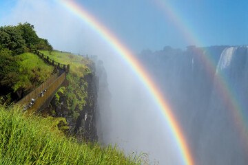 Bridge path near the cliff of Victoria Falls, Zimbabwe with double rainbow. Way to the paradise. Ecotourism waterfall.