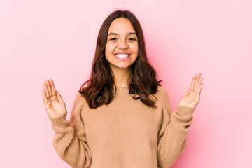 Young mixed race hispanic woman isolated holding something little with forefingers, smiling and confident.