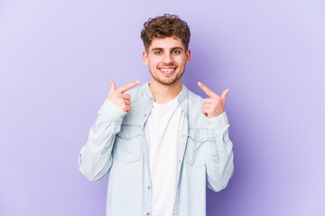 Young blond curly hair caucasian man isolated smiles, pointing fingers at mouth.