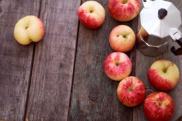 Red apples lie on a wooden board with dry spikes. Green blurred background